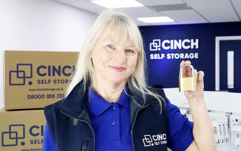 Storage near Newcastle. Image shows a Cinch Self Storage employee standing in front of the logo holding a padlock. 